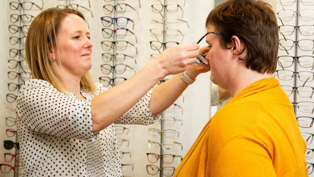 A woman has her glasses fitted at an optician