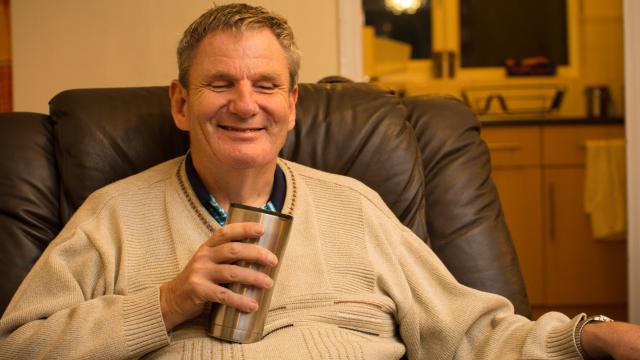 Sam with a cup of tea in his home