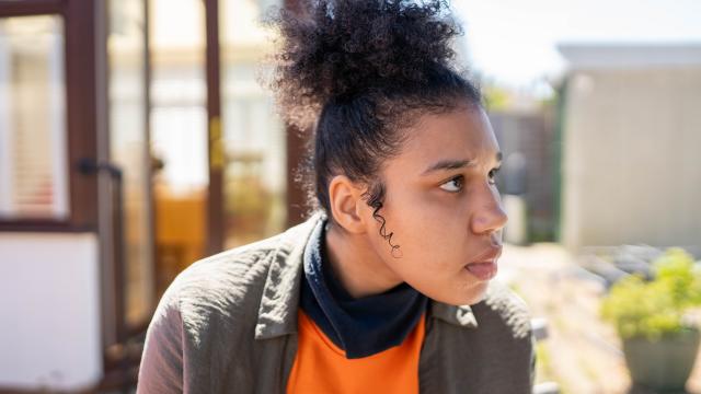 Candace wearing an orange tshirt looking in to the distance