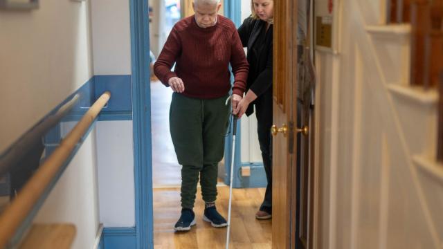 Rob being supported to use his cane for sight loss