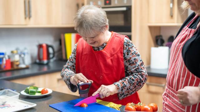 Sammy cooking in her kitchen with a supporter