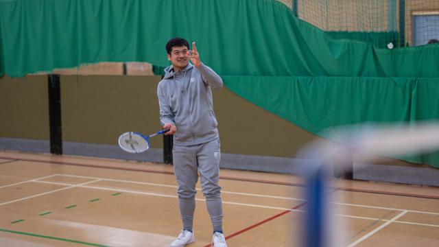 Giban playing badminton in a grey tracksuit