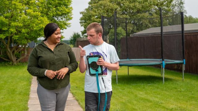 Jake and his support worker in the garden with an iPad