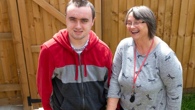 Luke and a Support Worker smiling outside