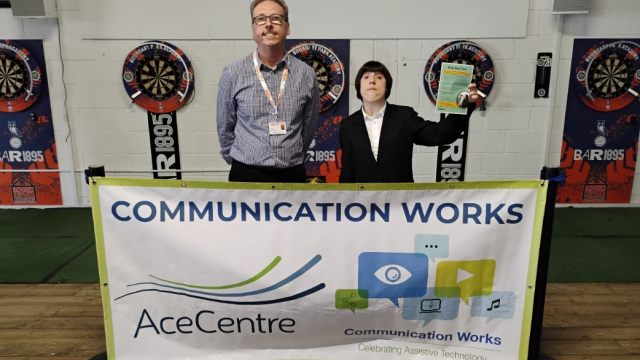 Steve and Rebecca stand behind a large banner which says 'Communication Works 2026'